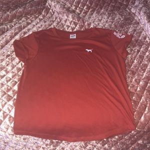 Burnt orange top with pink logo on the left sleeve